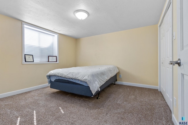 bedroom with carpet, a textured ceiling, and baseboards