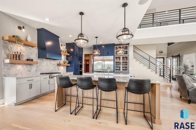 kitchen featuring a kitchen breakfast bar, extractor fan, backsplash, open shelves, and appliances with stainless steel finishes