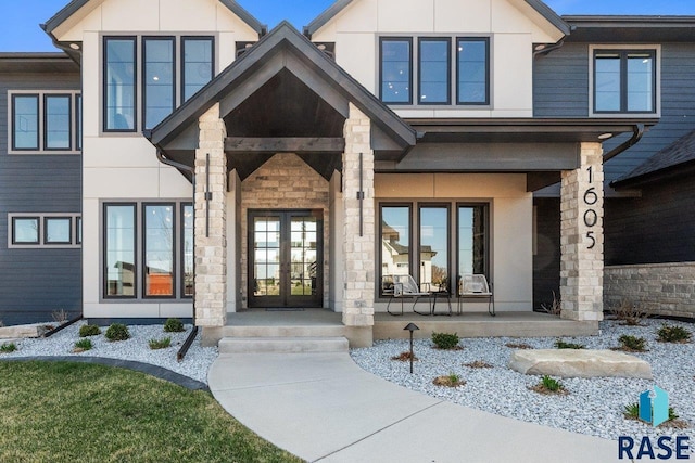 view of exterior entry featuring french doors, a porch, and stone siding