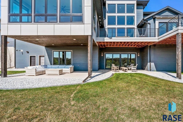 back of property featuring a lawn, an outdoor living space, a patio area, and a balcony