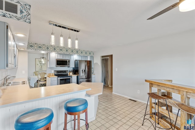 kitchen with stainless steel appliances, light countertops, visible vents, and a sink