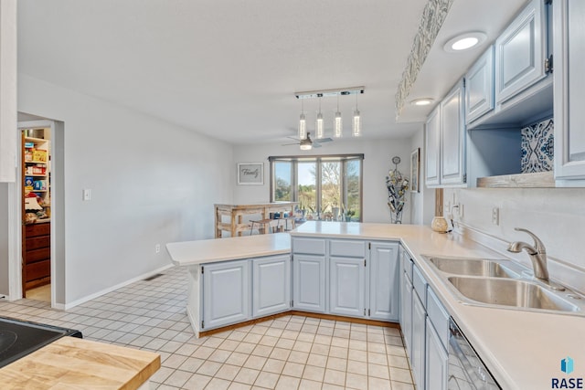 kitchen featuring a sink, light tile patterned floors, ceiling fan, light countertops, and a peninsula