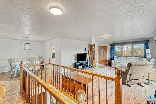 living area with a textured ceiling, light wood finished floors, and baseboards