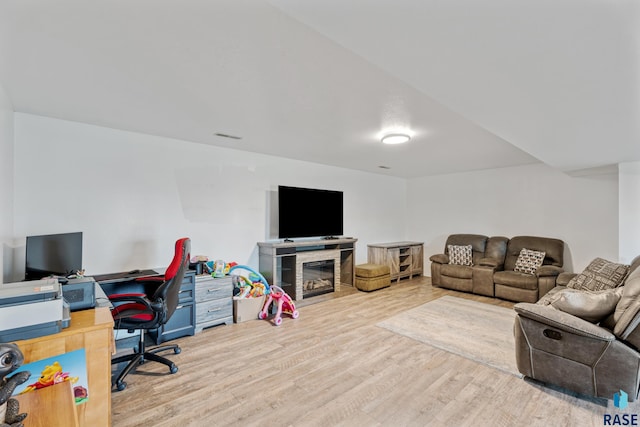living area with visible vents, a tiled fireplace, and wood finished floors