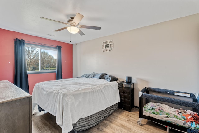bedroom with light wood-type flooring, visible vents, and ceiling fan