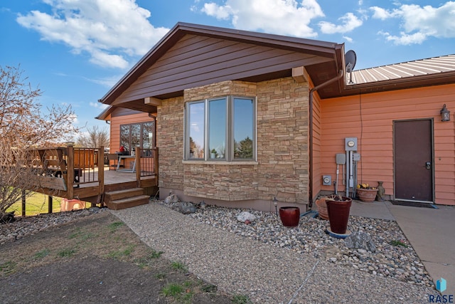view of front of property with stone siding, metal roof, and a deck