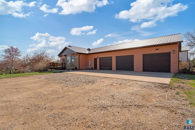 view of front of home with a wooden deck, dirt driveway, an attached garage, and metal roof
