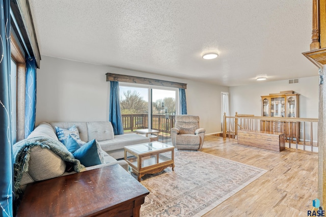 living area featuring wood finished floors, visible vents, and a textured ceiling