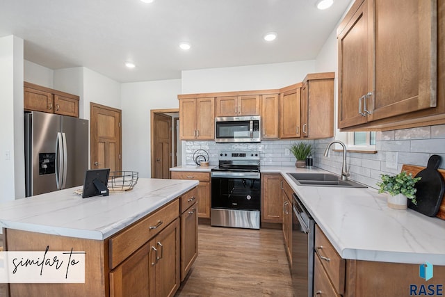 kitchen featuring brown cabinets, appliances with stainless steel finishes, decorative backsplash, and a sink