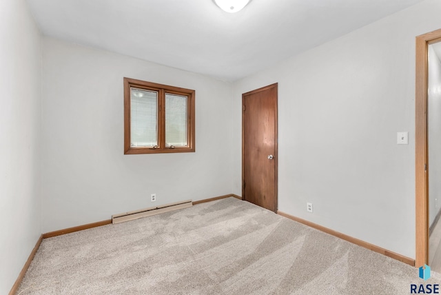 unfurnished bedroom featuring a baseboard heating unit, baseboards, and carpet flooring
