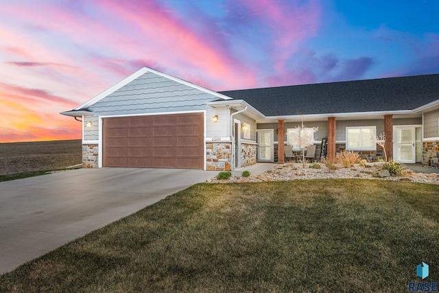 ranch-style home featuring stone siding, a lawn, a garage, and concrete driveway