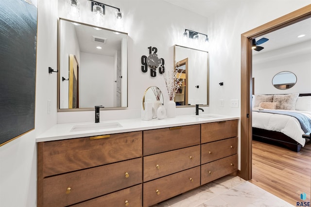 ensuite bathroom featuring double vanity, visible vents, ensuite bathroom, and a sink