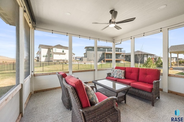 sunroom / solarium with plenty of natural light, an outdoor hangout area, a residential view, and ceiling fan