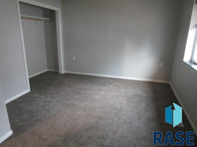 unfurnished bedroom with baseboards, carpet flooring, and a closet