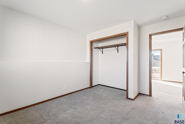 unfurnished bedroom featuring baseboards, carpet floors, and a closet