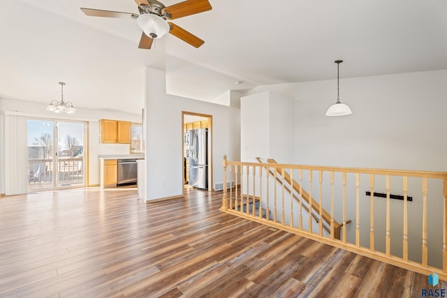 unfurnished living room with lofted ceiling, wood finished floors, visible vents, and ceiling fan with notable chandelier