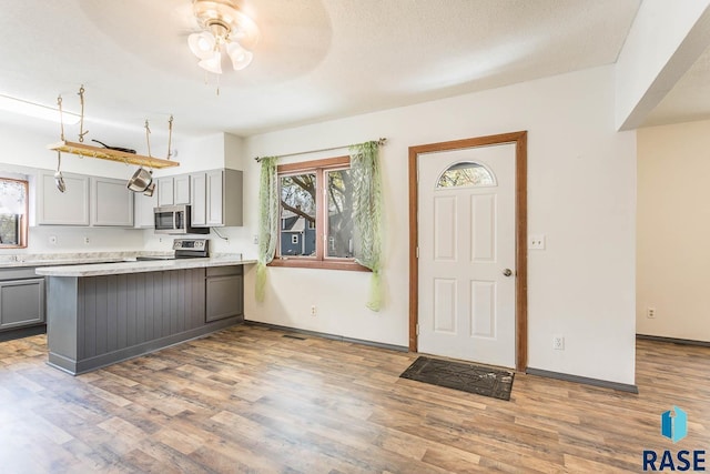 kitchen featuring wood finished floors, plenty of natural light, gray cabinets, ceiling fan, and stainless steel appliances