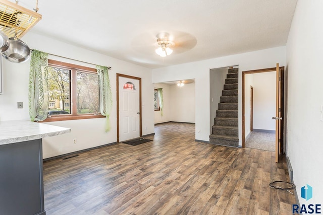 unfurnished living room featuring wood finished floors, a healthy amount of sunlight, stairs, and ceiling fan