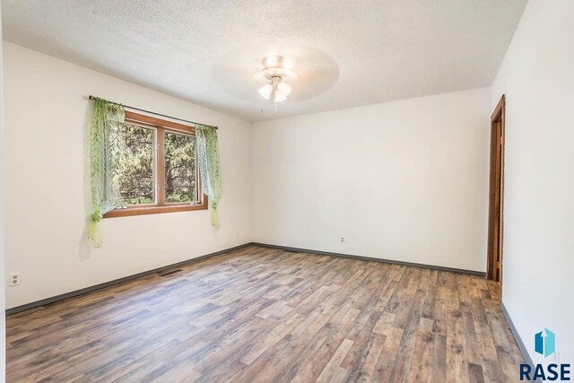 spare room featuring ceiling fan, baseboards, wood finished floors, and a textured ceiling
