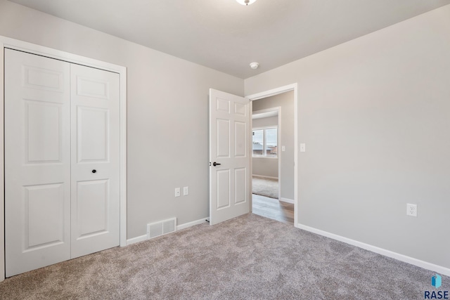 unfurnished bedroom with carpet floors, a closet, visible vents, and baseboards