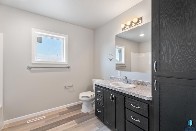 full bathroom with toilet, wood finished floors, vanity, baseboards, and visible vents