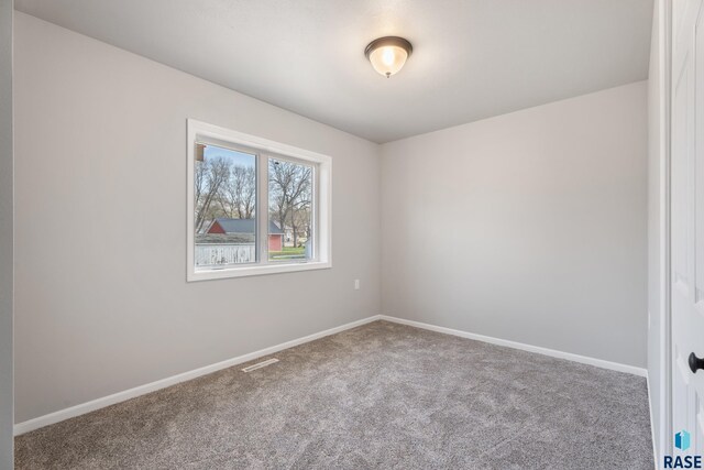 carpeted empty room featuring baseboards