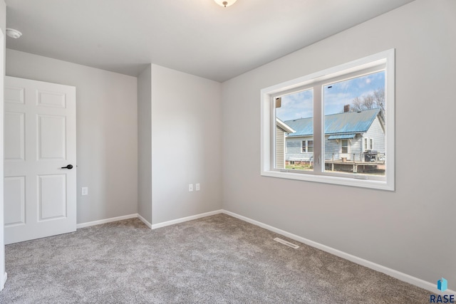 carpeted spare room featuring visible vents and baseboards