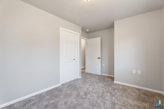 unfurnished bedroom featuring baseboards, carpet, and a closet