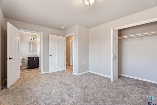unfurnished bedroom featuring ensuite bath, baseboards, a closet, and light colored carpet