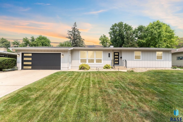 view of front facade featuring a front lawn, driveway, a garage, and board and batten siding