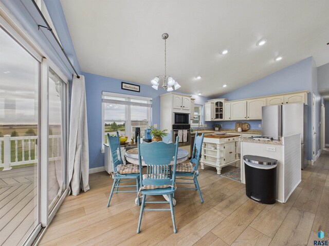 kitchen with a sink, black microwave, an inviting chandelier, oven, and light wood finished floors