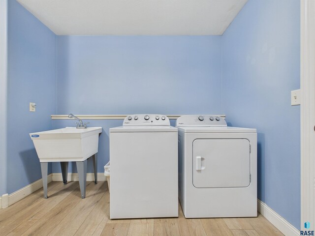 clothes washing area with washing machine and clothes dryer, wood finished floors, laundry area, and baseboards