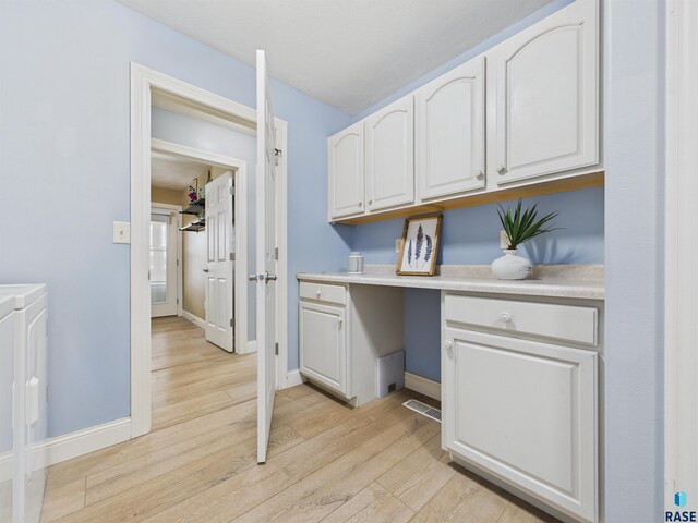 washroom featuring baseboards, light wood-type flooring, visible vents, and cabinet space