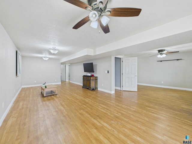 unfurnished living room featuring baseboards, a ceiling fan, and light wood finished floors
