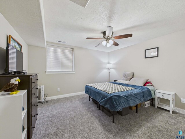 bedroom with carpet flooring, a textured ceiling, visible vents, and baseboards