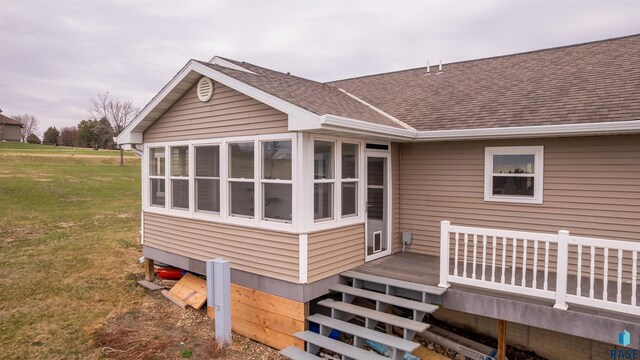 rear view of property featuring a lawn, a wooden deck, and a shingled roof
