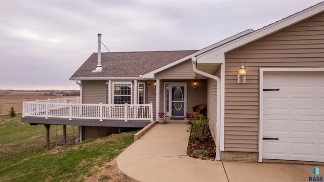 view of front of house featuring a garage, a shingled roof, and a deck