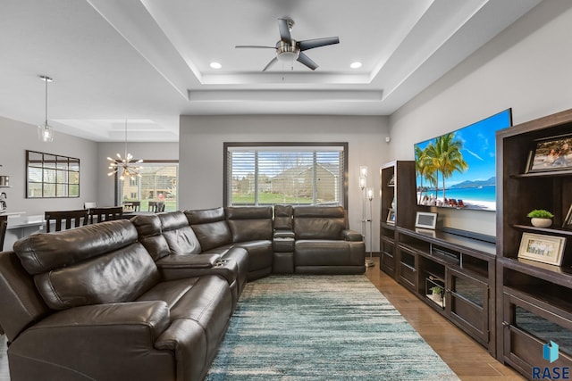 1917 S Firefly Dr, Sioux Falls, SD 57110 - living area featuring a raised ceiling, light wood-type flooring, recessed lighting, and ceiling fan with notable chandelier