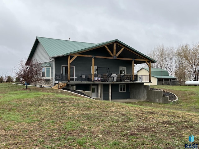 back of property with a yard, a wooden deck, and metal roof