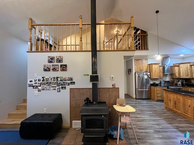 living room featuring a wood stove, high vaulted ceiling, stairway, and dark wood finished floors