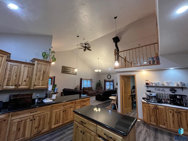 kitchen featuring ceiling fan with notable chandelier, high vaulted ceiling, dark countertops, and dark wood-style flooring
