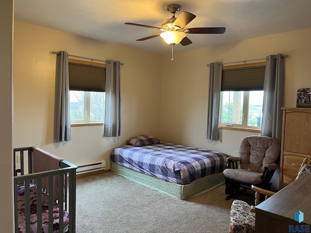 carpeted bedroom with a baseboard heating unit, multiple windows, and ceiling fan