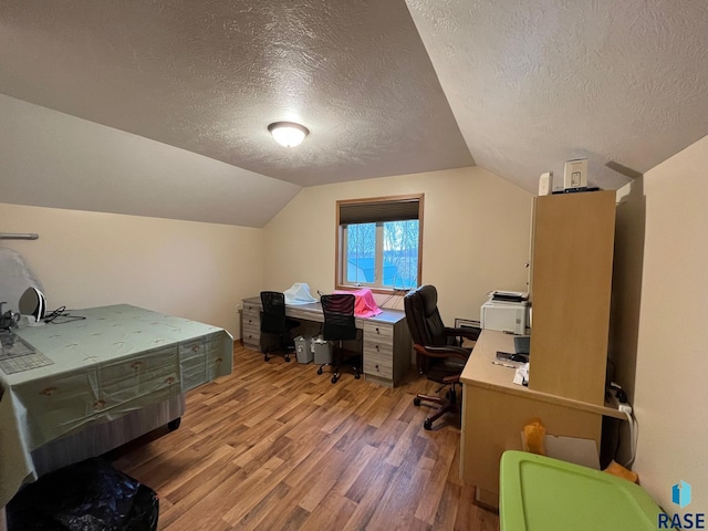 office featuring light wood finished floors, a textured ceiling, and lofted ceiling