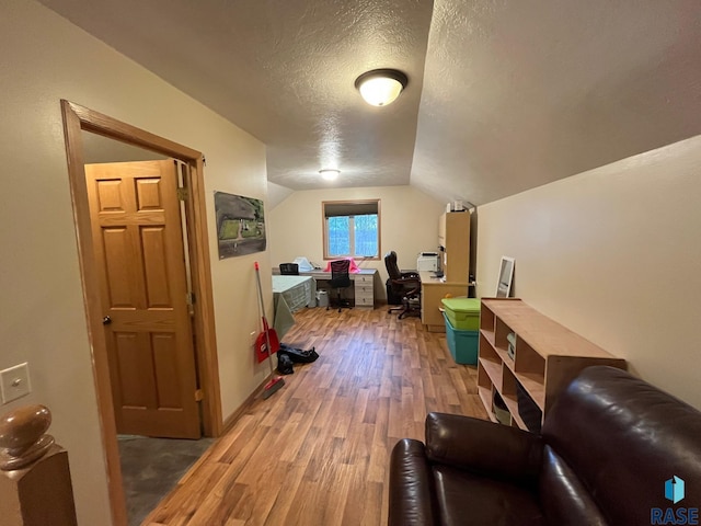 additional living space with a textured ceiling, light wood-style flooring, and vaulted ceiling