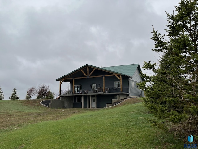 back of house with metal roof, a wooden deck, and a yard