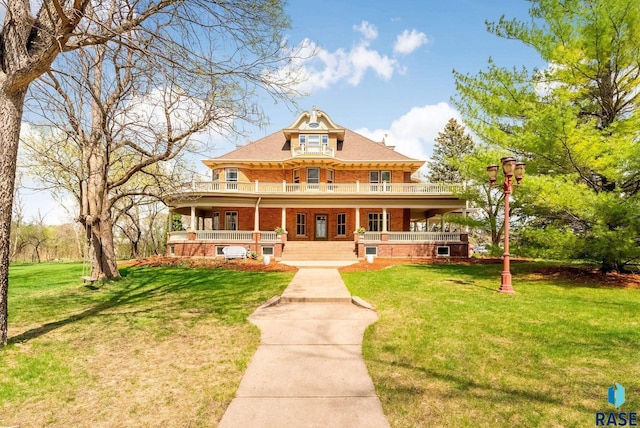 view of front of house featuring a front lawn, a balcony, covered porch, and brick siding