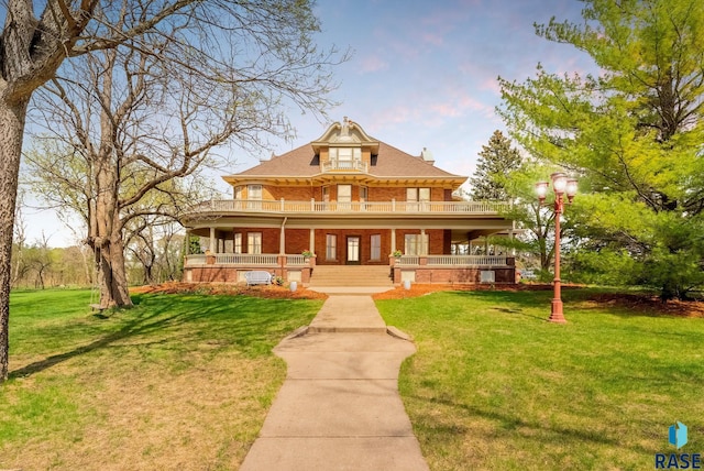 view of front of property with brick siding, a porch, a balcony, and a front yard