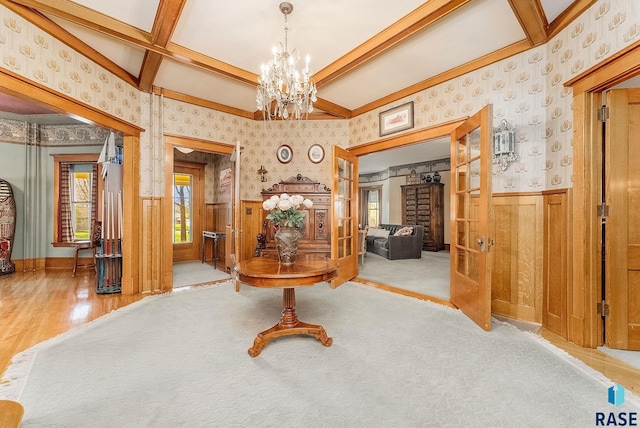 hallway featuring beamed ceiling, a wainscoted wall, coffered ceiling, wallpapered walls, and an inviting chandelier