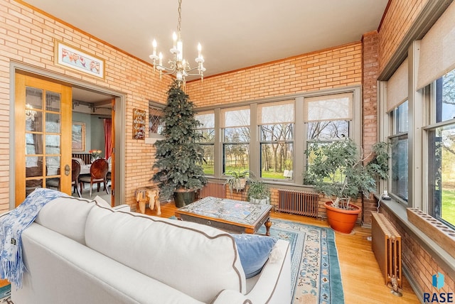 living area featuring an inviting chandelier, brick wall, and radiator