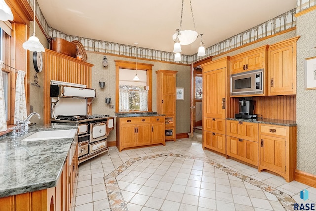 kitchen with wallpapered walls, a sink, range with gas cooktop, and stainless steel microwave